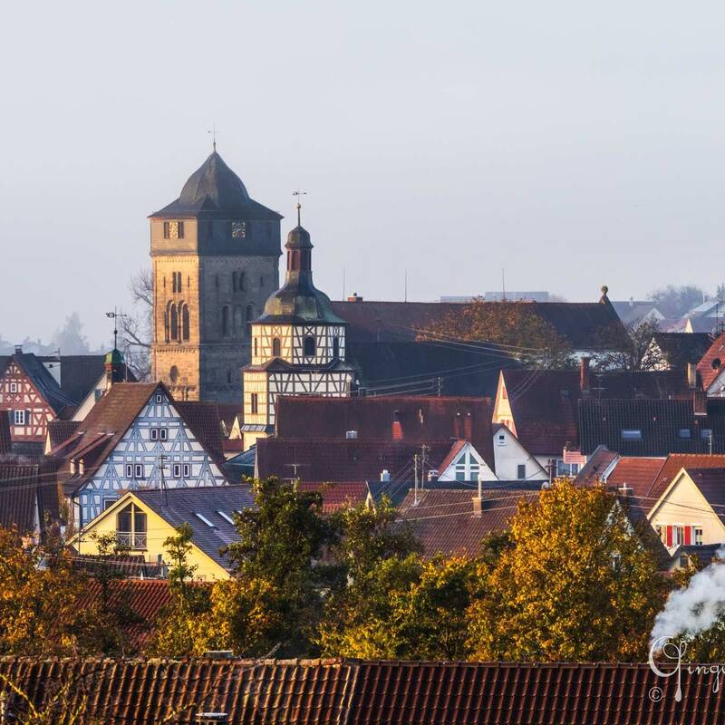 Dorfkirche und Stiftskirche mittig auf Foto im Vordergrund rauchender Kamin