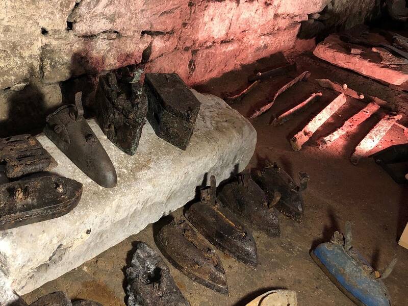 alte Bügeleisen und weitere Gegenstände aus Metall im Gewölbekeller aufgereiht